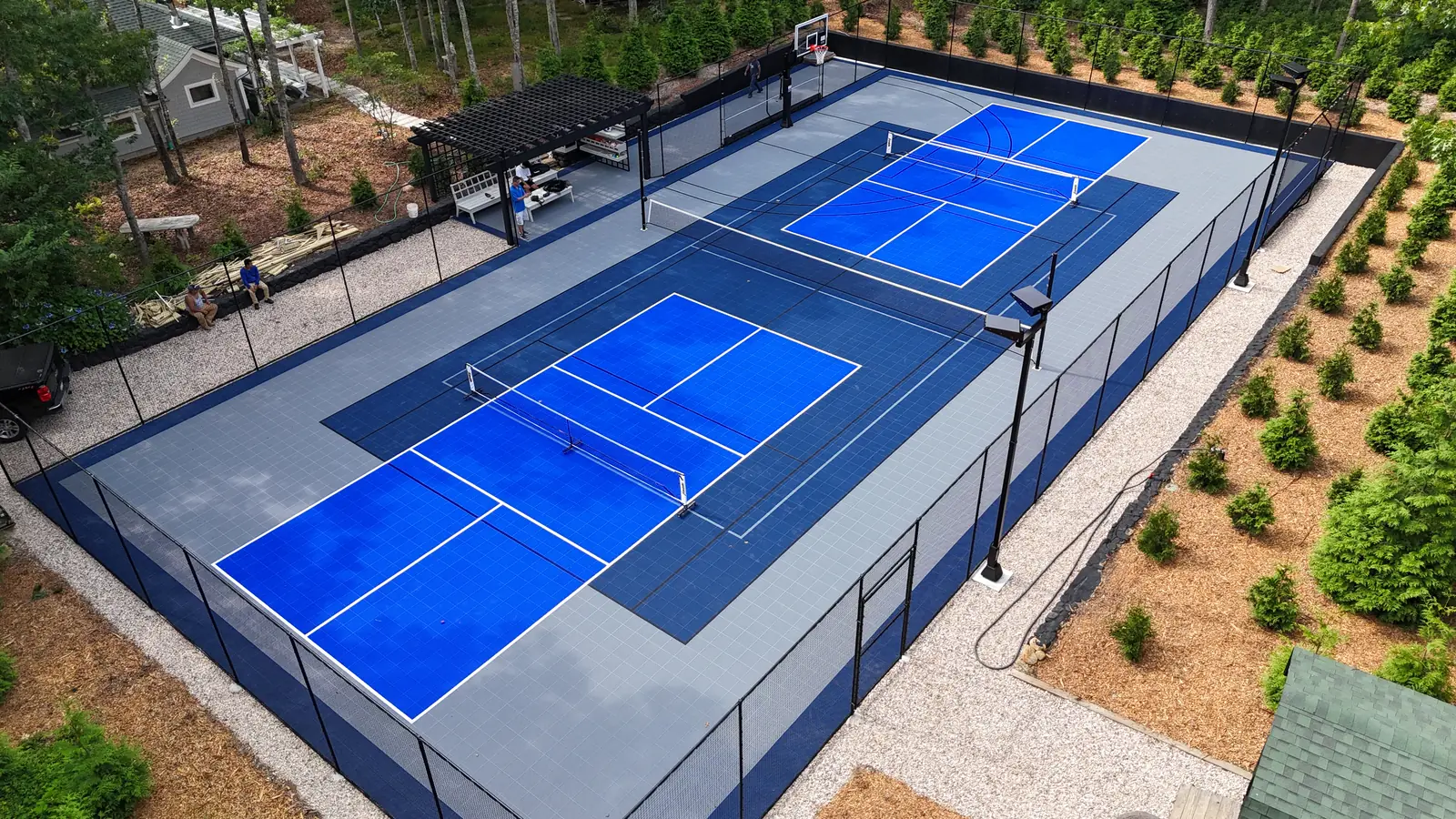 Large backyard court with pickleball nets, basketball hoop, and pergola