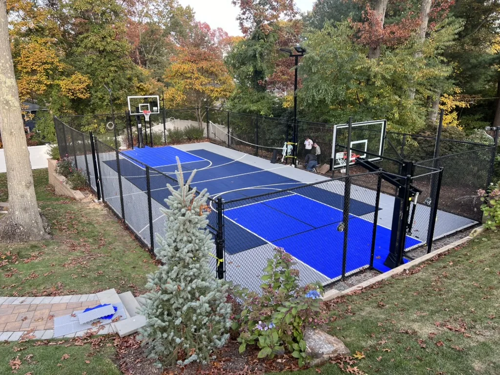 Finished blue court with fencing, hoops, and light poles