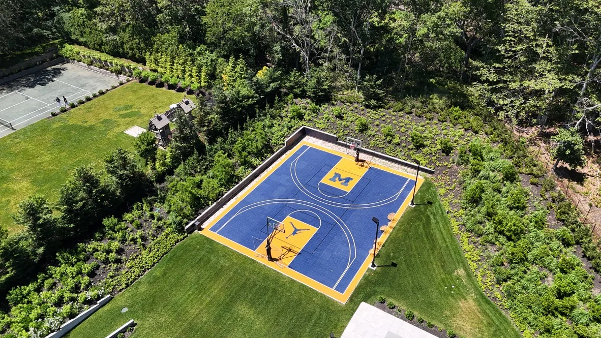 Blue and gold backyard court surrounded by turf and lawn