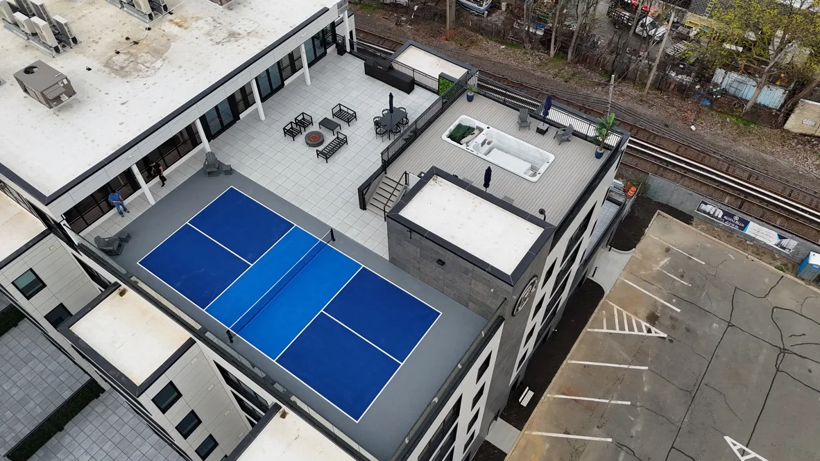 Rooftop pickleball court on a commercial building with a deck and seating