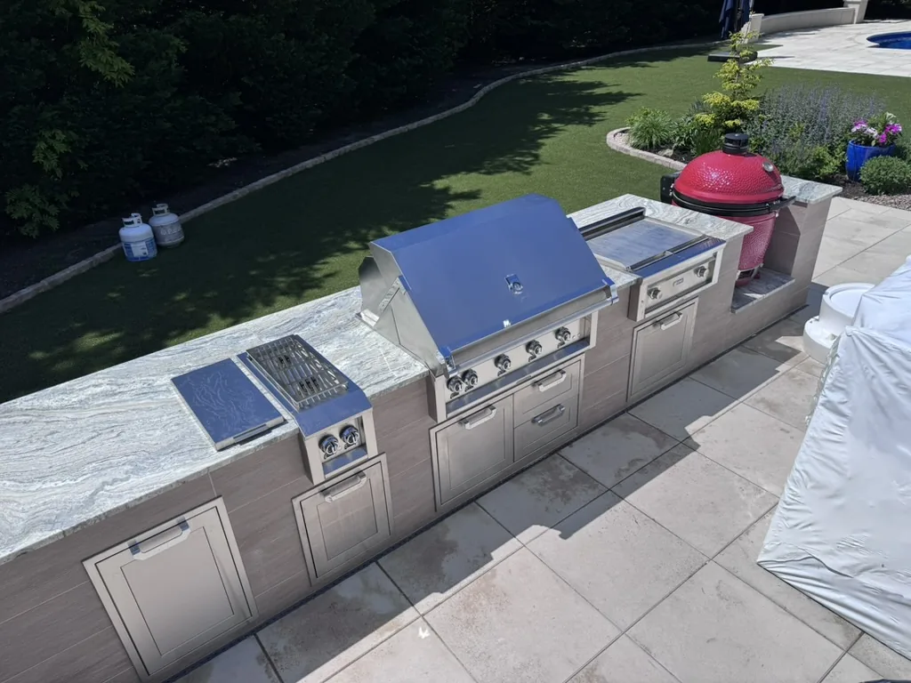Stone outdoor kitchen with granite counters on a paver patio