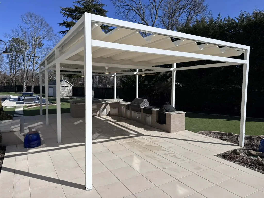 White pergola with retractable canopy over an outdoor kitchen patio