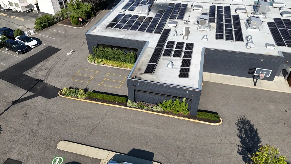 Aerial view of the office building before the work, with plain asphalt parking beside the building and a single wall mounted hoop